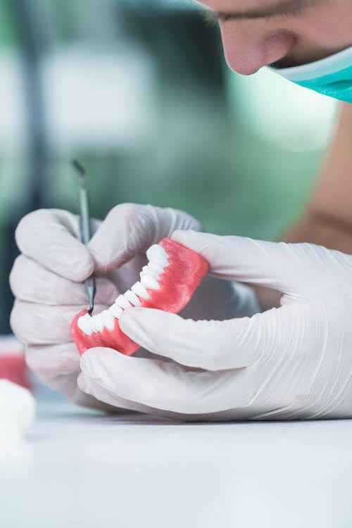 Dental Prosthesis, Dentures, Prosthetics Work. Prosthetics Hands While Working On The Denture, False Teeth, A Study And A Table With Dental Tools.