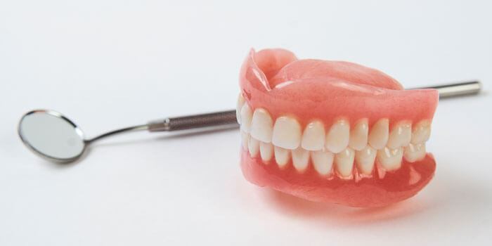 Artificial Teeth On A White Background With Copy Space.